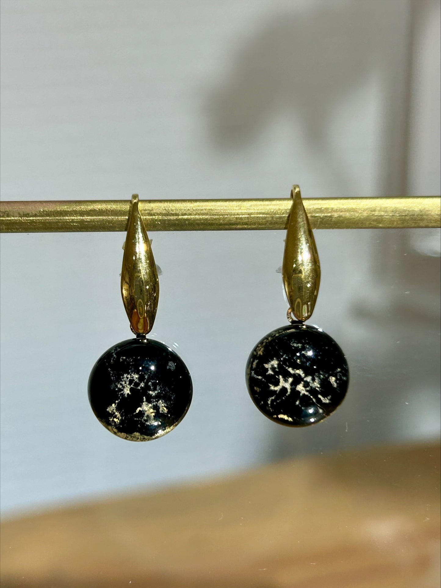 Boucles d'oreilles artisanat d'art en métal doré et résine noire à inclusions dorées, bijou fait main unique éco-responsable.
