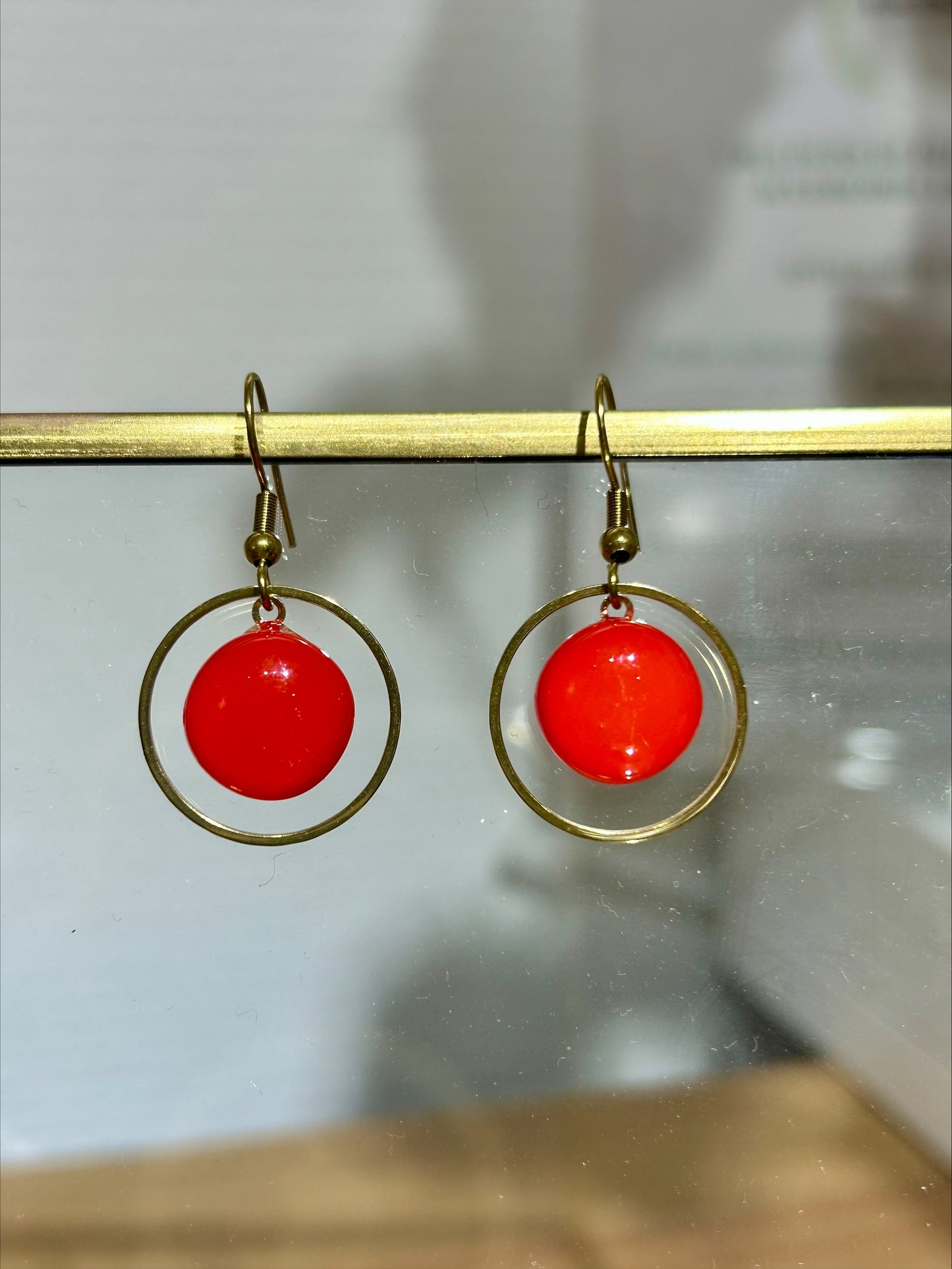 Boucles d'oreilles artisanales en métal doré avec disque rouge éclatant, bijou fait main unique, produit éco-responsable.