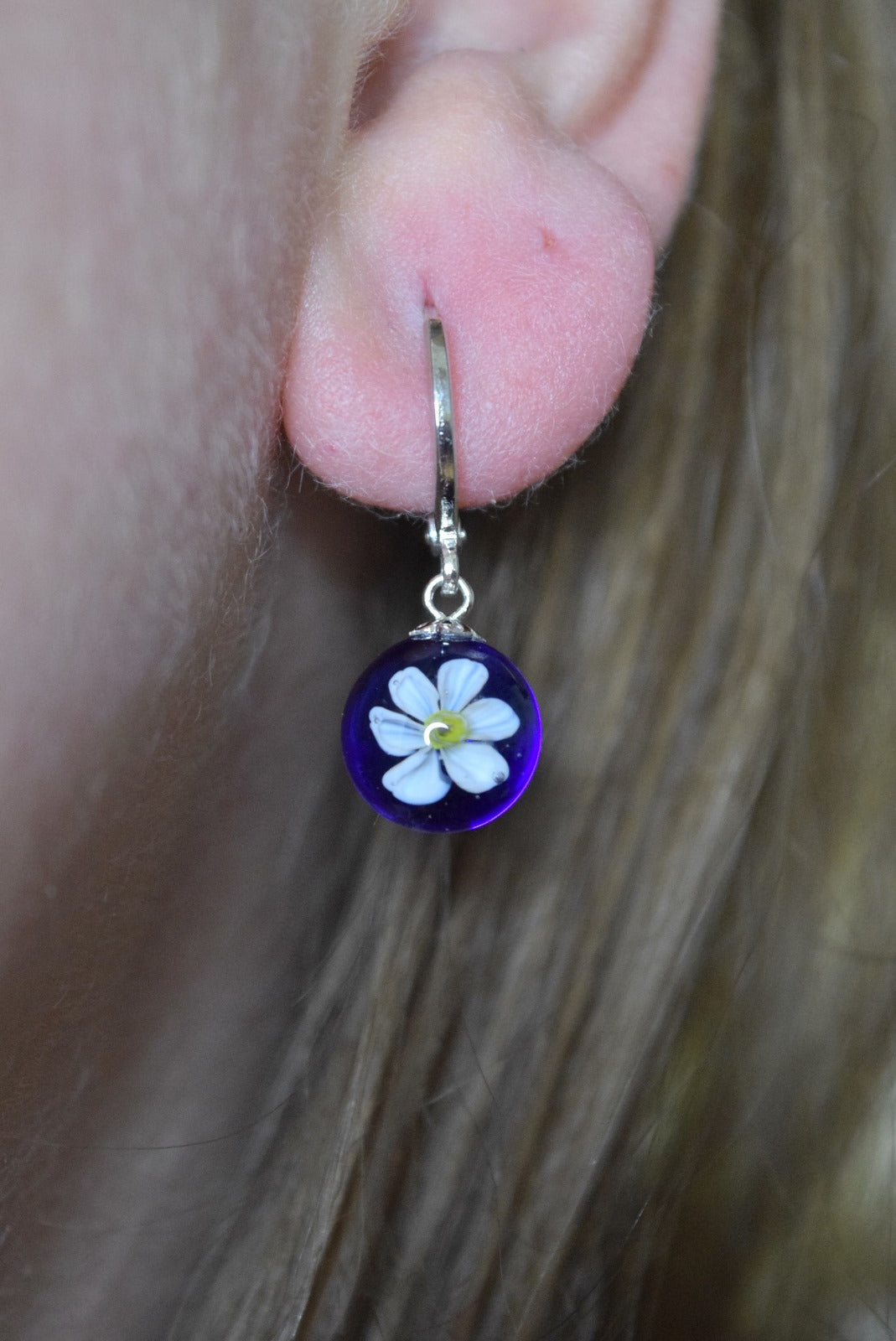 Créole artisanale en verre bleu avec fleur de narcisse blanche délicate, bijou fait main éco-responsable.