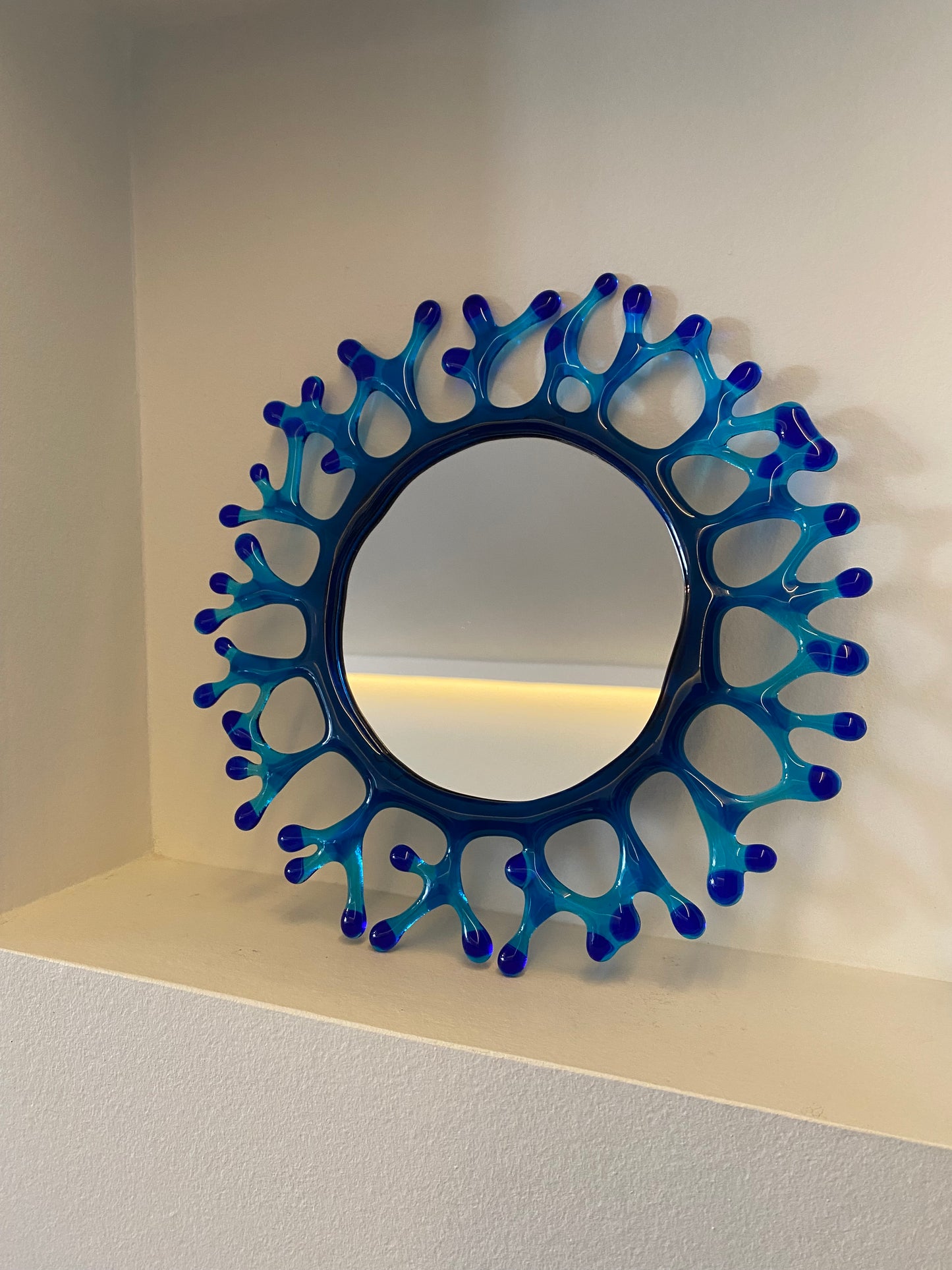 Miroir rond en verre bleu avec cadre corail artisanal, décoratif et éco-responsable, œuvre unique.