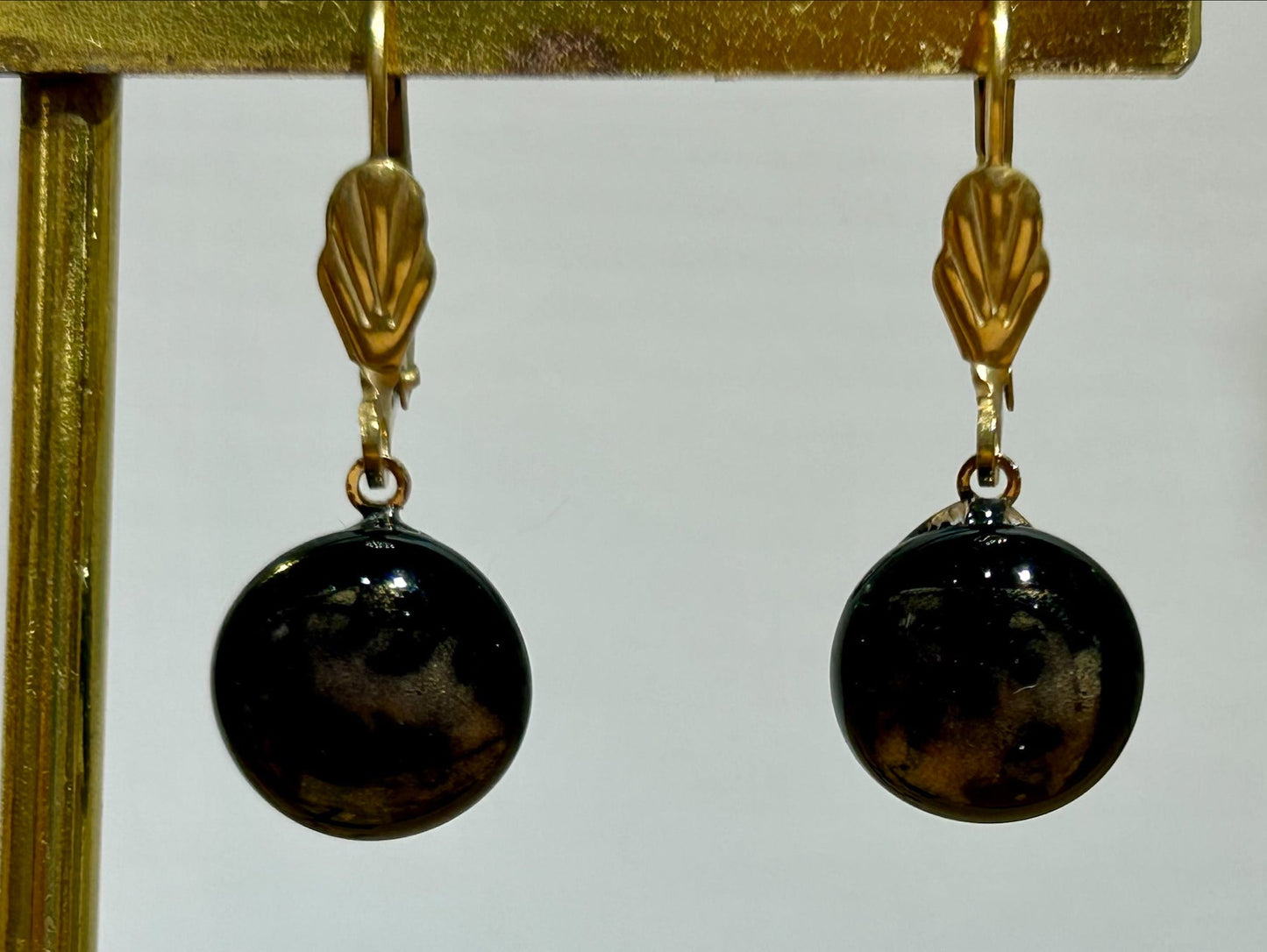 Boucles d'oreilles artisanales en métal doré et perles noires brillantes, bijou fait main, œuvre unique, produit.