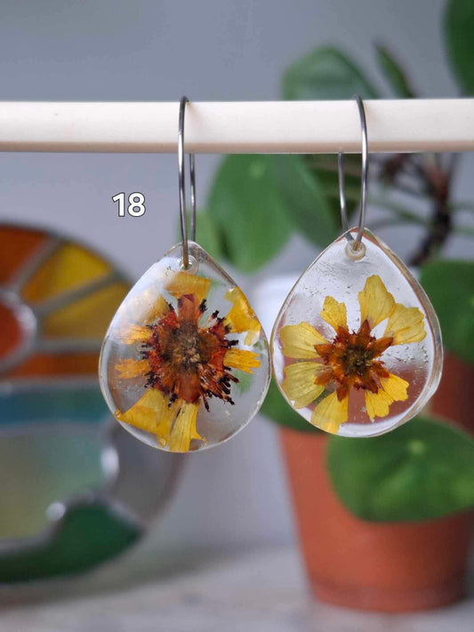 Boucles d’oreilles artisanales en résine transparente avec fleurs séchées jaunes, bijou fait main, œuvre unique, produit.