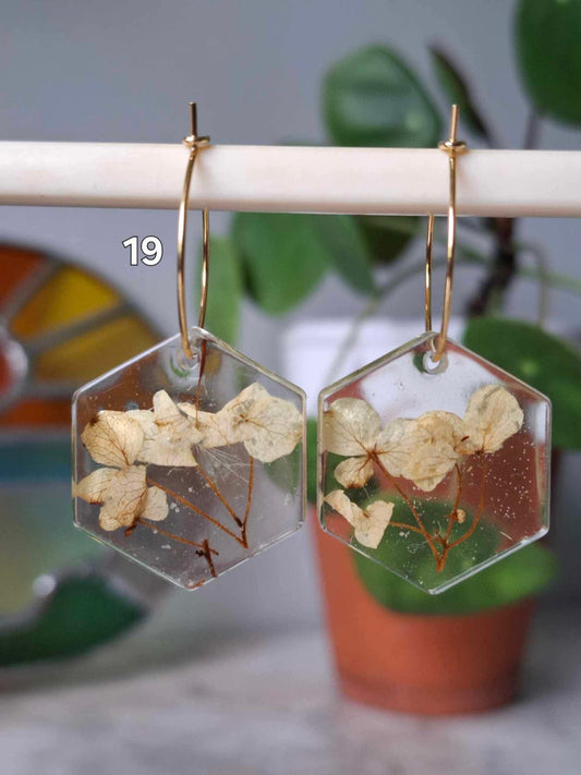 Boucles d’oreilles artisanales hexagonales en résine claire avec fleurs séchées naturelles, bijou fait main éco-responsable.