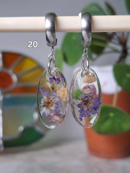 Boucles d’oreilles artisanales en résine transparente avec fleurs séchées colorées, bijou fait main, produit.