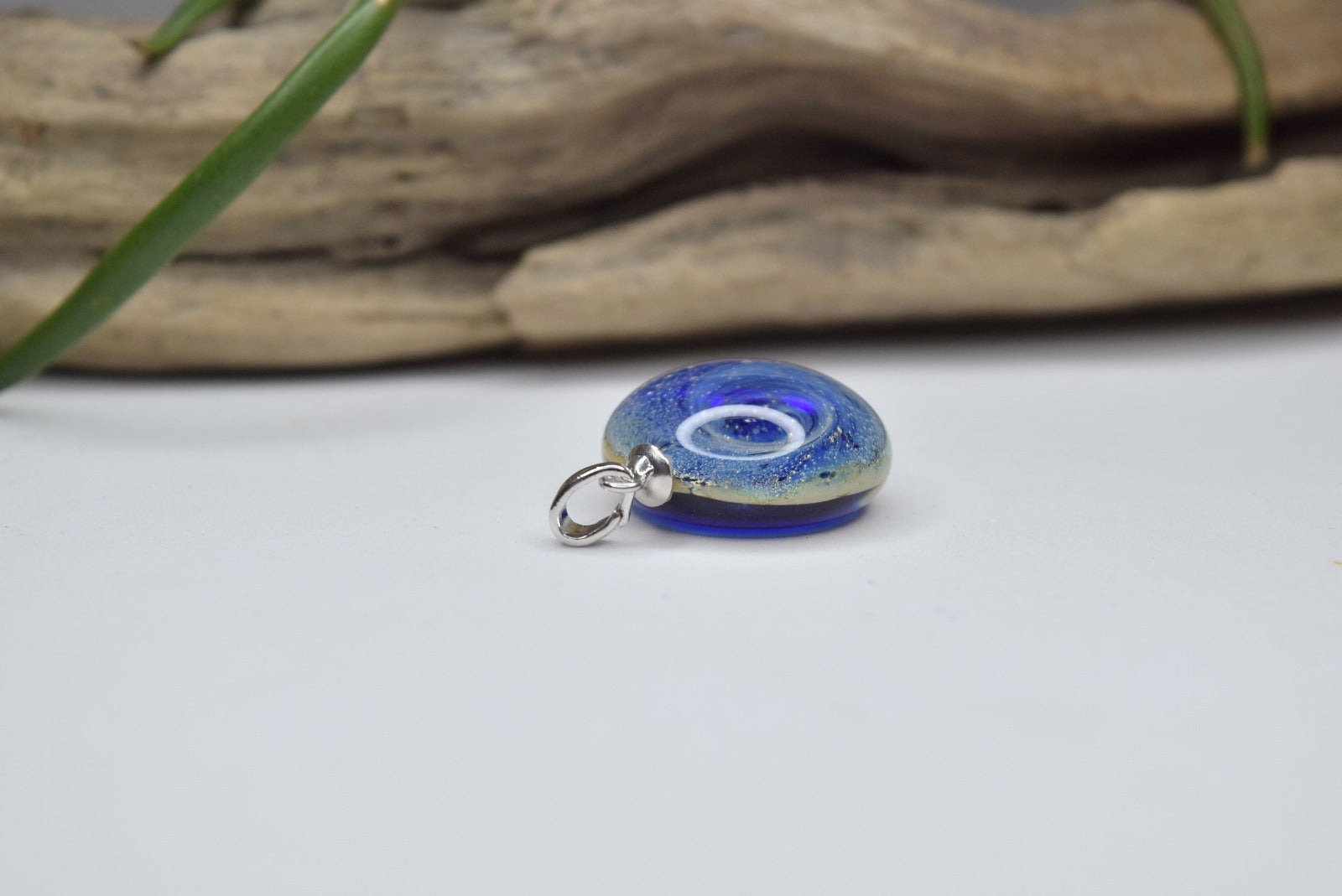 Pendentif rond en verre Murano bleu avec motifs tourbillonnants, bijou fait main et œuvre unique d'artisanat d'art écologique.
