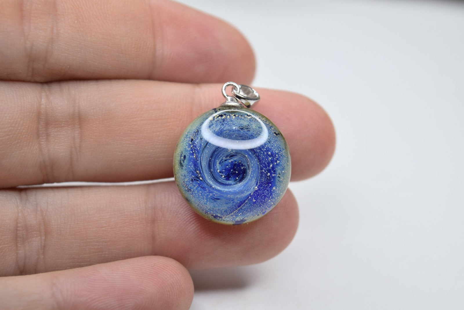 Pendentif rond en verre Murano bleu avec motifs tourbillonnants, bijou fait main et œuvre unique d'artisanat d'art écologique.