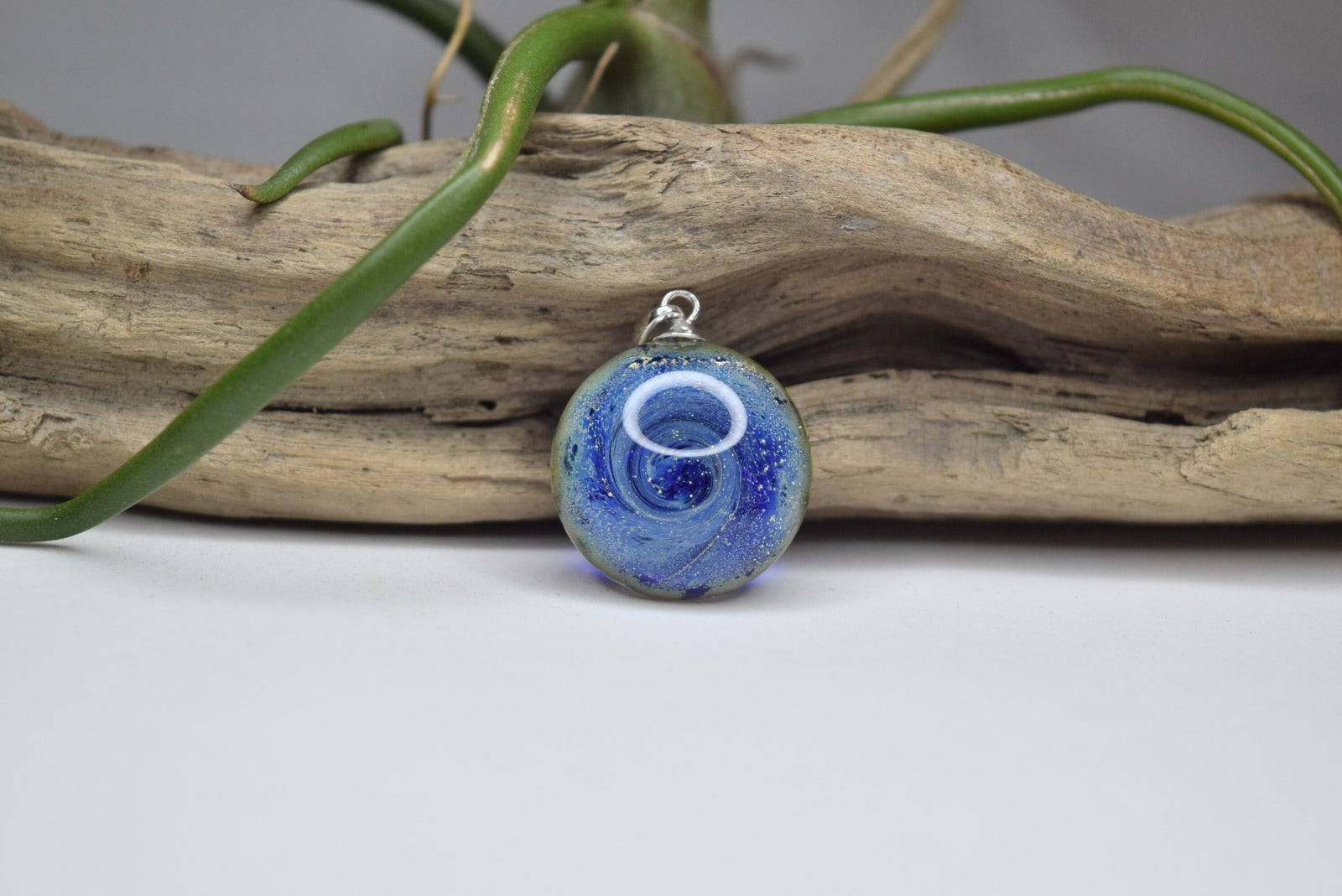 Pendentif rond en verre Murano bleu avec motifs tourbillonnants, bijou fait main et œuvre unique d'artisanat d'art écologique.
