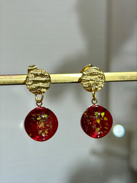 Boucles d'oreilles artisanat d'art en résine rouge translucide avec incrustations dorées, bijou fait main éco-responsable.
