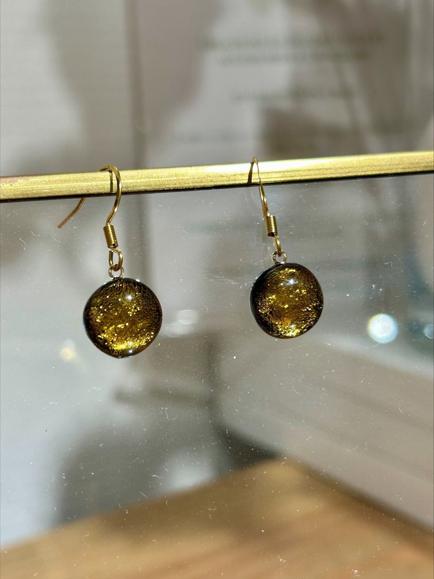Boucles d'oreilles artisanales rondes en résine dorée brillante, bijou fait main éco-responsable unique.