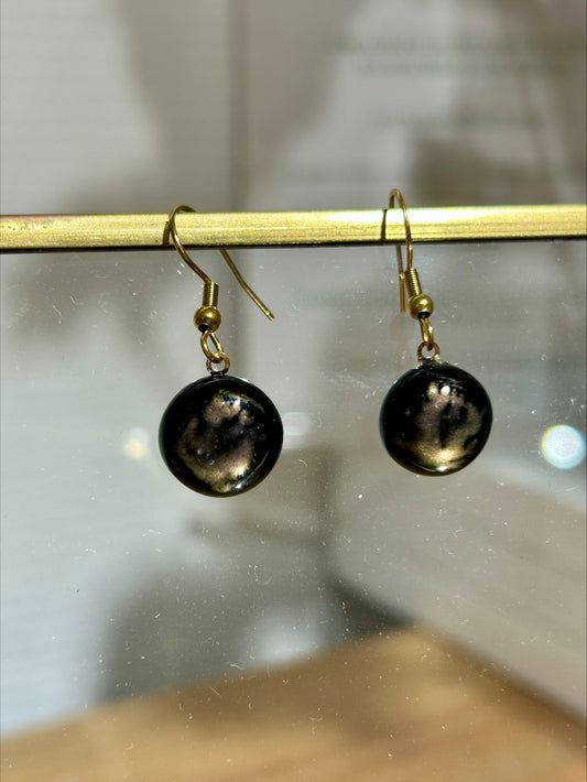 Boucles d'oreilles artisanales rondes en résine noire avec inclusions dorées, bijou fait main unique, produit.