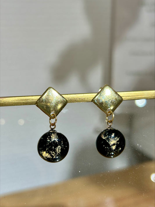 Boucles d'oreilles en métal doré artisanales avec pendants ronds noirs décorés, bijou fait main unique, produit.